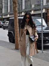 a lady wears a trench coat with white pants and black top